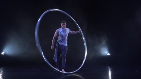 male muscular acrobat shows difficult tricks for a balance and concentration while spinning on a cyr wheel