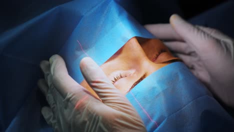 corrección de la visión con láser. un paciente y un equipo de cirujanos en la sala de operaciones durante una cirugía oftalmológica. especulo del párpado. tratamiento de lasik. paciente bajo una cubierta estéril
