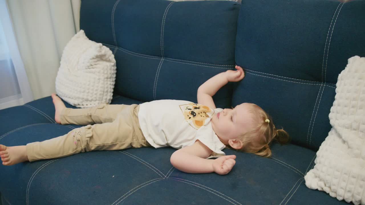 Bambina che riposa serenamente su un divano blu.