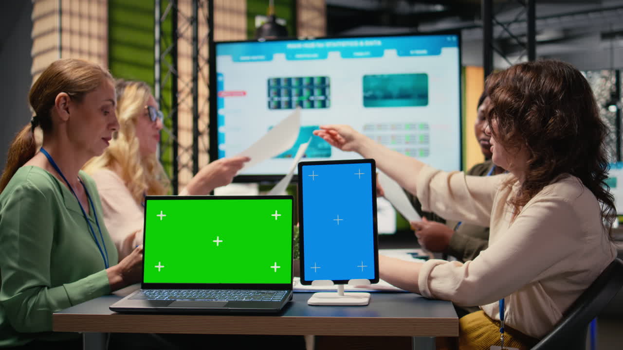 Businesswomen working side by side with a green screen on the table