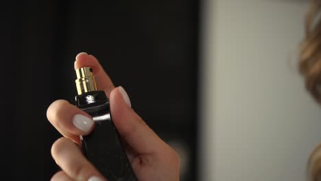 una mujer sostiene perfume en sus manos y los salpica