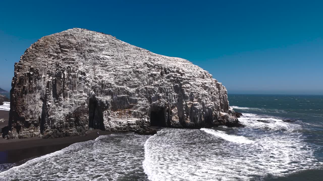 Luftfoto af Piedra de la Iglesia-søjlerne og sort sandstrand i Constitución, Chile ved solnedgang
