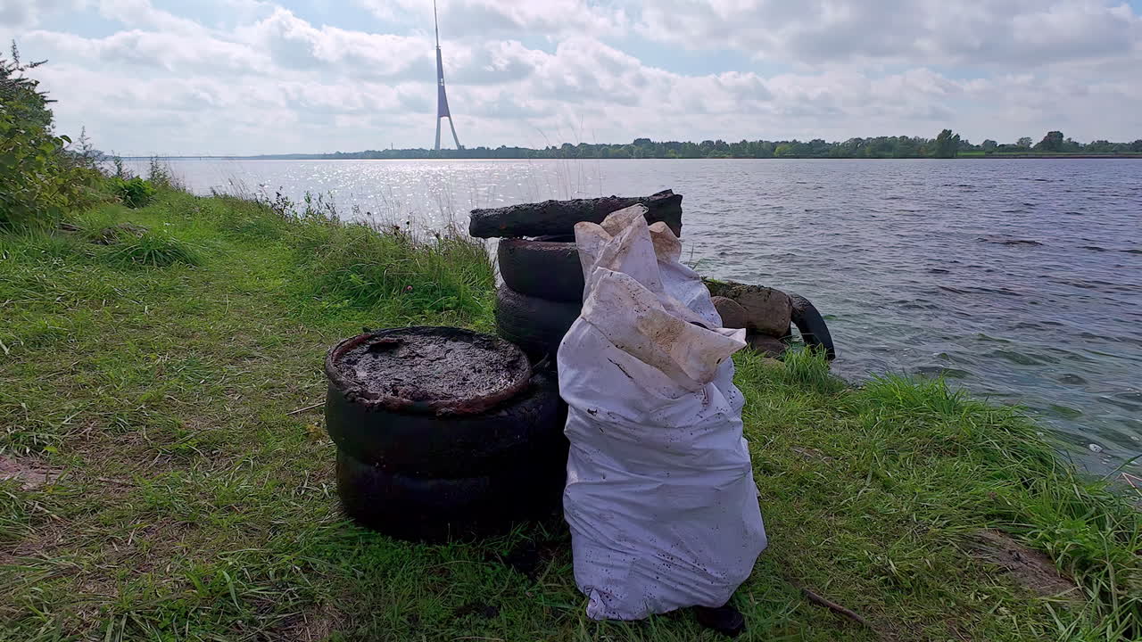 Stack Of Old Tires And Sack Of Garbage On The Shore