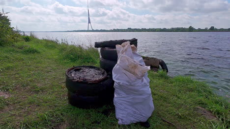 stack of old tires and sack of garbage on the shore