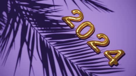 golden ballon 2024 on silhouetted palms purple background