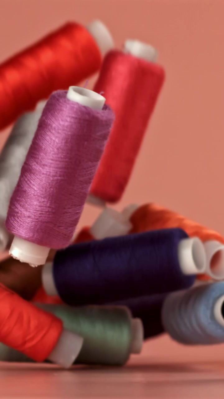 Colorful Spools of Thread Falling and Landing on a Surface