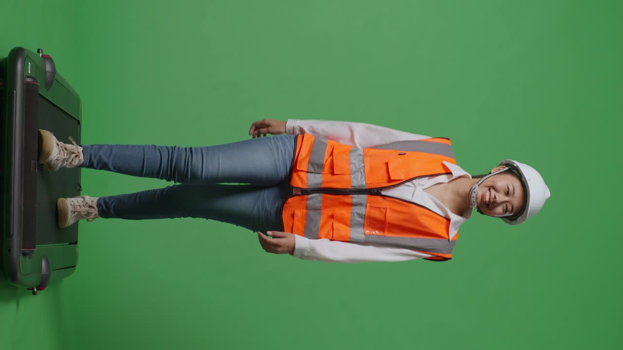 안전 헬을 입은 아시아 여성 엔지니어의 몸이 녹색 스크린 배경 스튜디오에서 는 동안 주위를 둘러보고 있습니다.