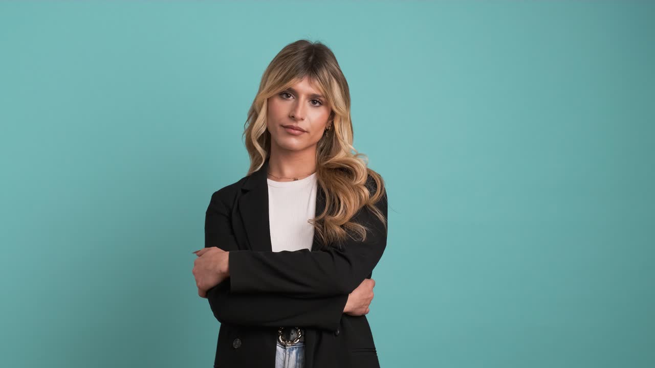 Confident transgender businesswoman posing with arms crossed on blue background