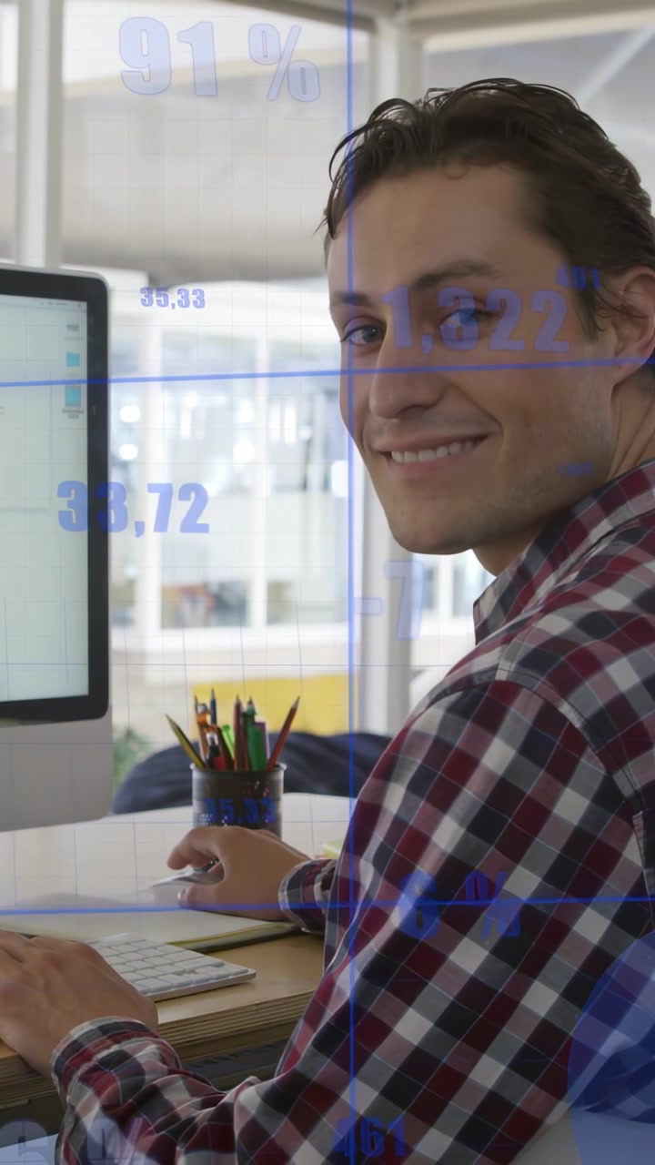 Video vertical: Hombre escribiendo en un entorno de negocios, mostrando superposiciones azules mientras revisa datos y sonríe.