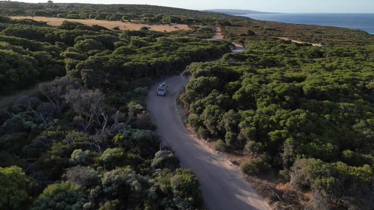 Seurantakuva valkoisesta pakettiautosta ajamassa maaseututietä pitkin auringonlaskun aikaan Margaret Riverin alueella, Länsi-Australiassa.