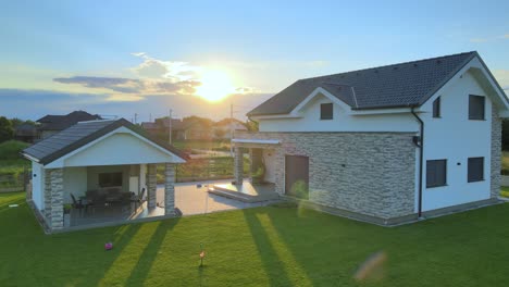 Aerial-view-approaching-a-modern-family-house-in-a-neighborhood,-during-sunset