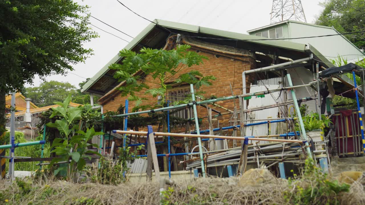 Old brick house with pipes and plants, showing traditional Chinese renovation work