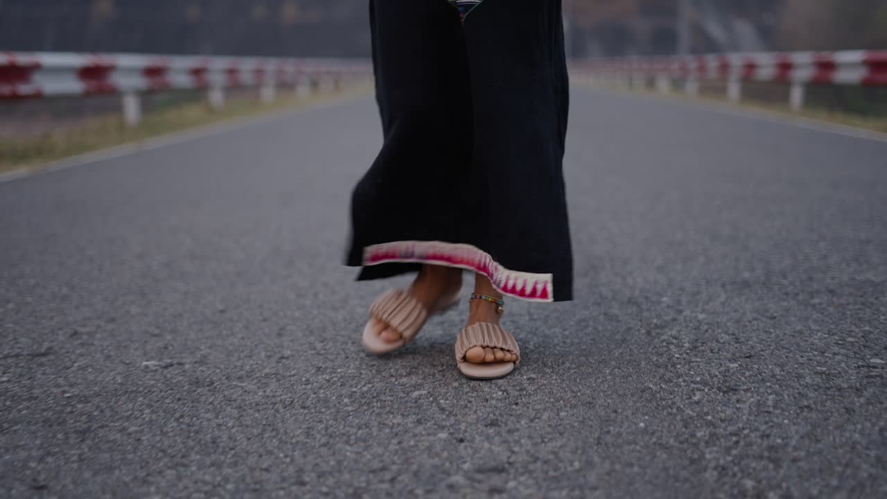 Person Walking on an Asphalt Road in Traditional Attire
