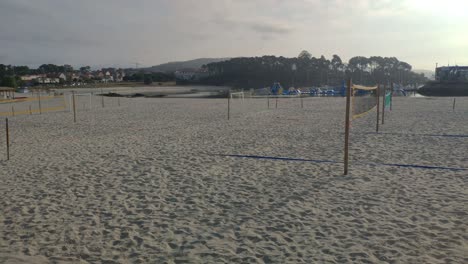 Zona-De-Playa-Con-Campo-De-Fútbol-En-La-Arena-Y-Voleibol-Sin-Gente-En-Una-Mañana-Nublada-De-Principios-De-Verano,-Tiro-Rodante-A-La-Derecha