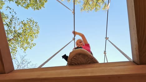 niña feliz jugando en la atracción de tarzán en el patio de recreo en el parque de atracciones
