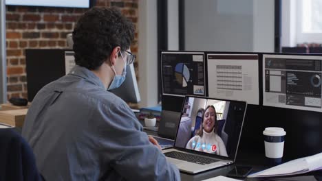 Caucasian-man-on-laptop-video-chat-wearing-face-mask-in-office