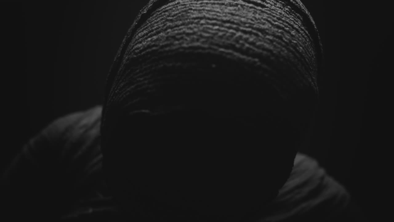 A mummy of a woman on a dark backdrop turns her head
