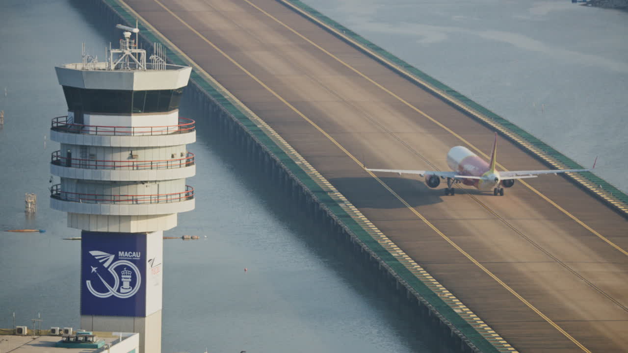 Verkehrsflugzeug auf der Startbahn neben dem Fluglotsenturm am Flughafen Macau