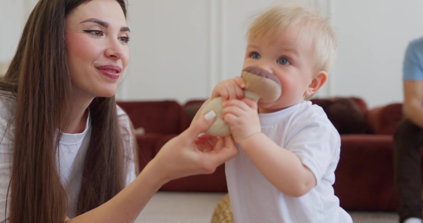 Smiling Mother Encourages Baby to Walk with a Toy