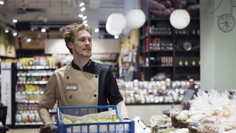 a man in a special uniform carries fruits to a cart in a grocery store