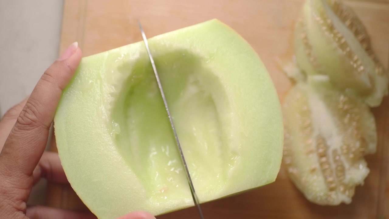 Close-up of a Hand Slicing a Fresh Green Melon