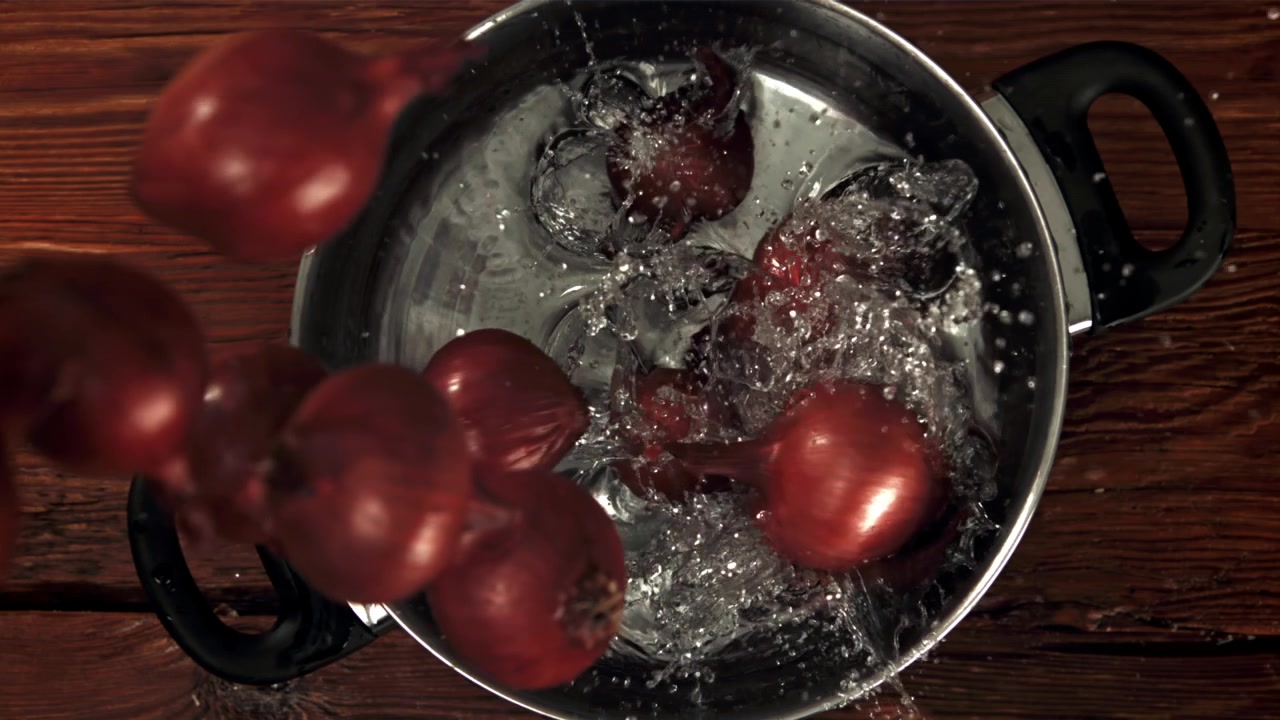 Red Onions Falling and Splashing into Water in a Pot