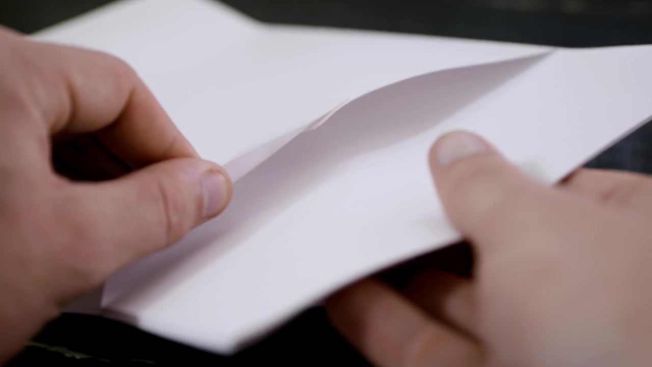 Putting a stock of paper inside an envelope. Close up of a man closing a letter and putting it in an envelope before mailing.