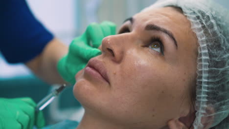 woman at procedure of anti-aging filler injection on cheek