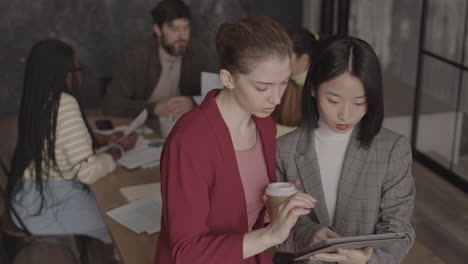 multiethnic female colleagues talking in office