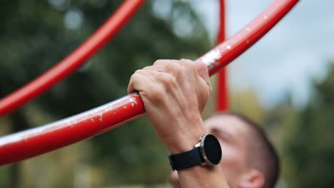 Man-trains-with-pull-ups-in-public-park-monitoring-training-session-with-smartwatch