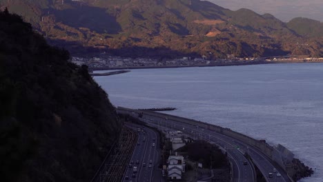 slow tilt up over car traffic on highway in japan with snowy mt
