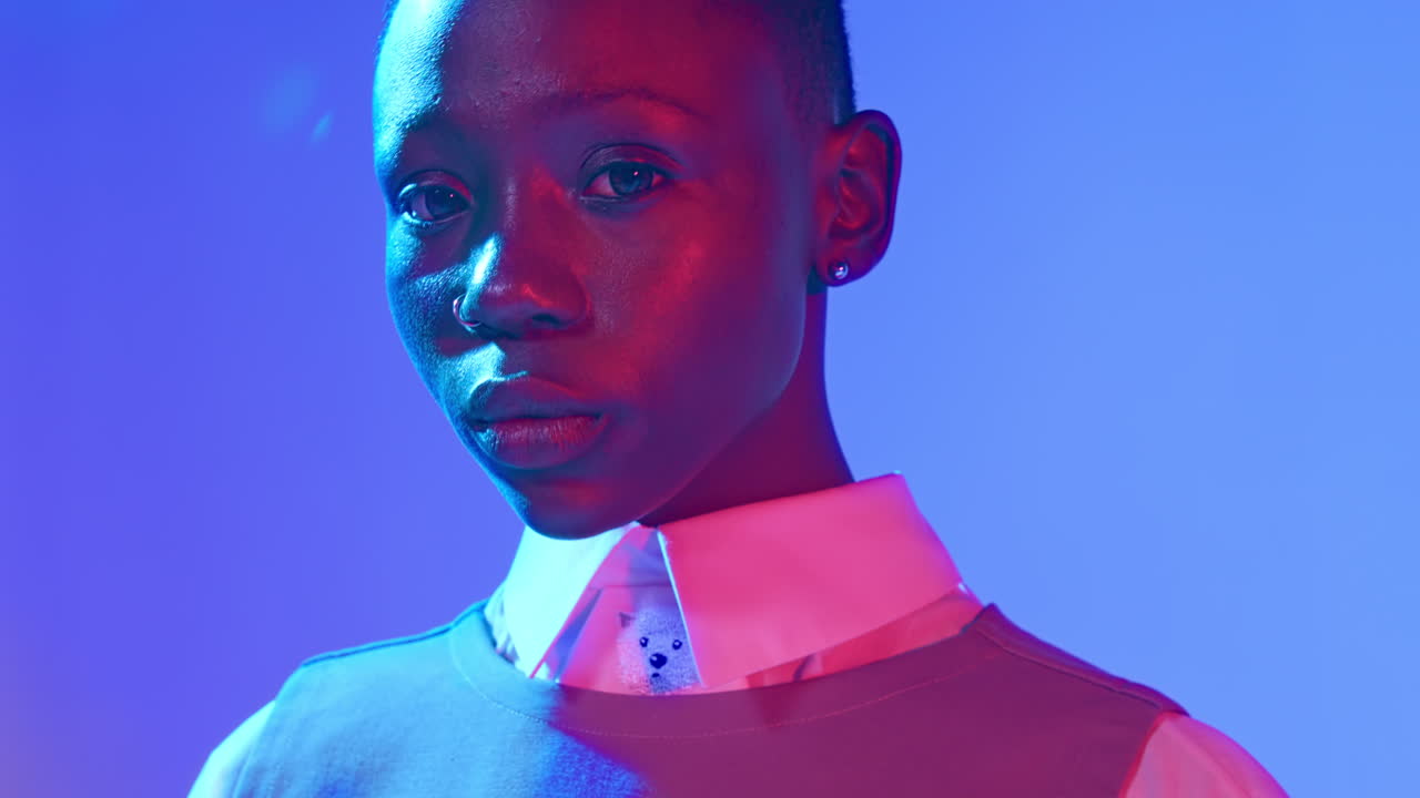 Primo piano estremo drammatico di una giovane modella afroamericana con luci da studio rosse e blu.