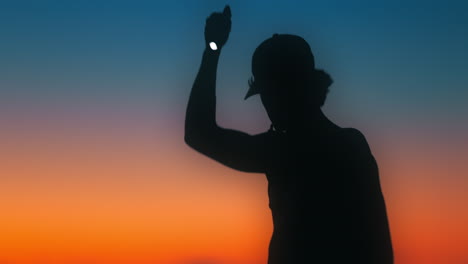 hiker shines flashlight around during sunset creating a chromatic flare. shot on canon r5 4k fine with rf 70-200mm f2.8 with chromatic flare filter.