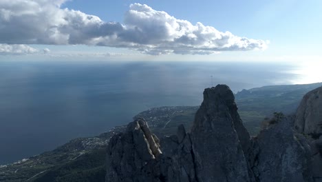 vista aérea del pico de la montaña rocosa con el océano y las nubes