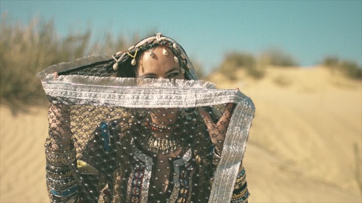 Gypsy woman dancing and playing with her hijab in the desert