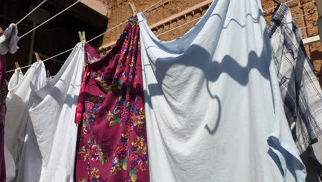 línea de lavado de ropa con clavijas de plástico y madera que sostienen ropa limpia lavada para secar al aire libre en el patio en un día soleado