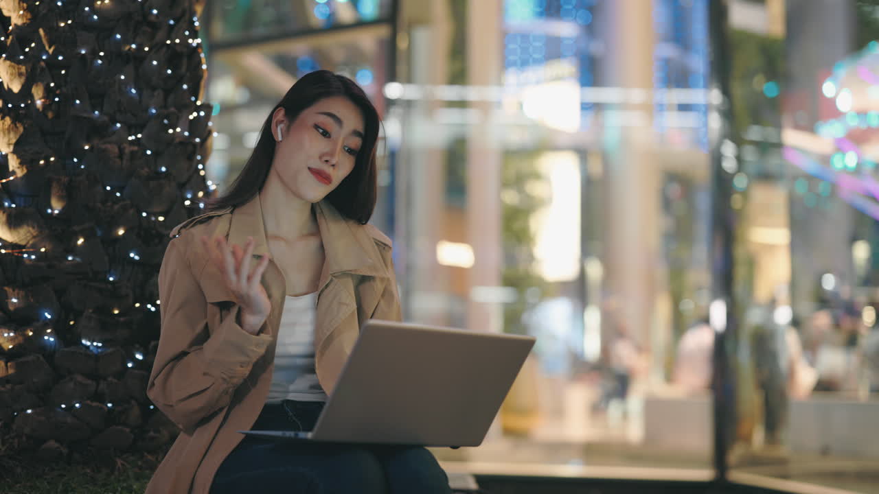 Woman working on laptop in a city at night