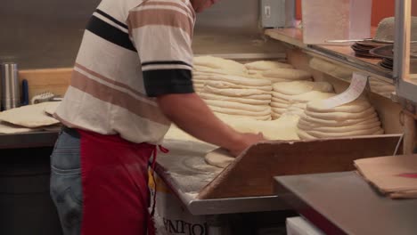 kitchen staff assembling dough, sauce and other ingredients for pizzas