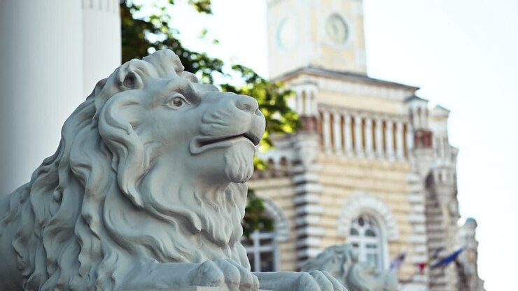 Primo piano di una statua di un leone bianco di fronte al municipio di Chisinau con dettagli architettonici classici sullo sfondo