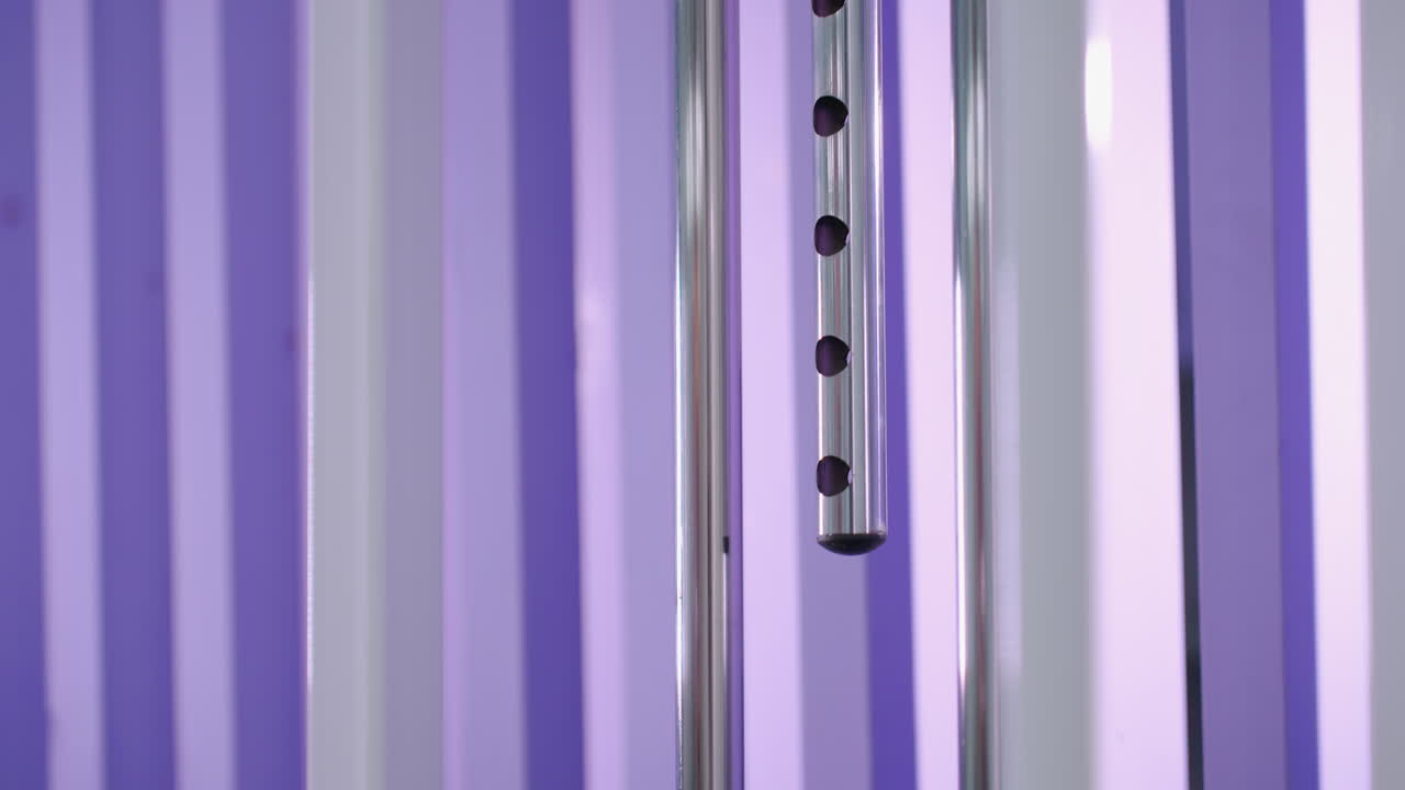 крупный снимок весовой стопки, спускающейся на тренажерное оборудование с металлическими решетками и ярким фиолетовым фоном, сосредоточьтесь на движении и тренировках сопротивления, когда вес спускается вниз