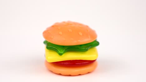 delicious mini gummi burger rotating on the the turn table isolated on white background. candy version of classic american foods - hamburger.