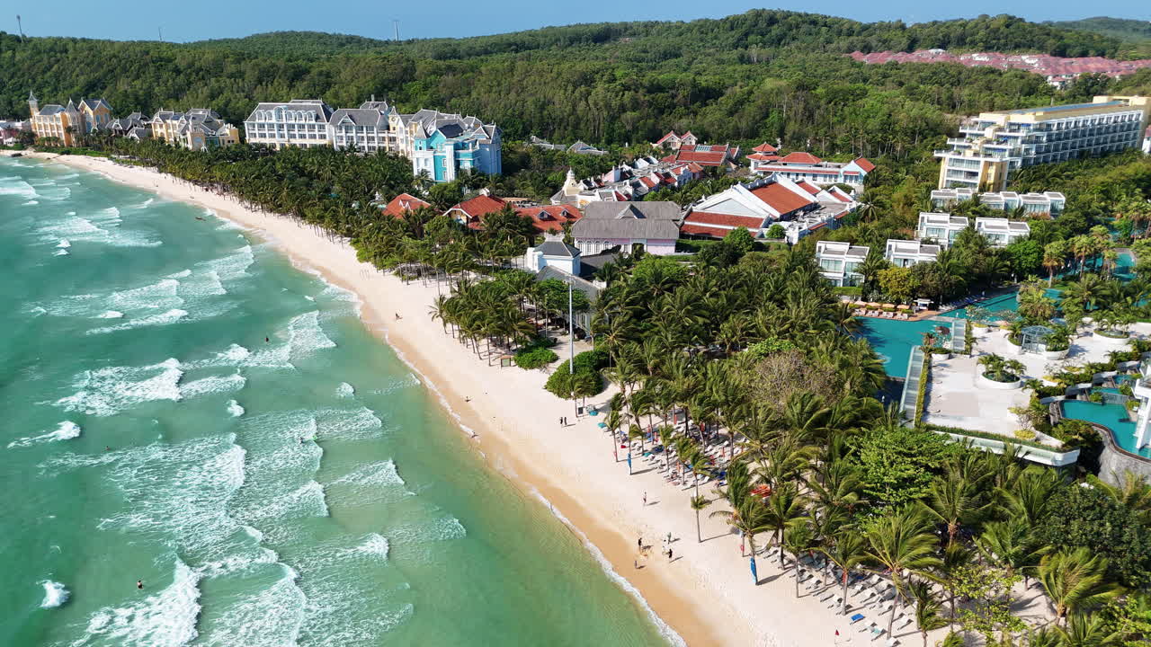 Quang cảnh từ flycam một khu nghỉ dưỡng bãi biển nhiệt đới với hàng dừa và sóng biển xanh ngọc dọc bờ biển Việt Nam