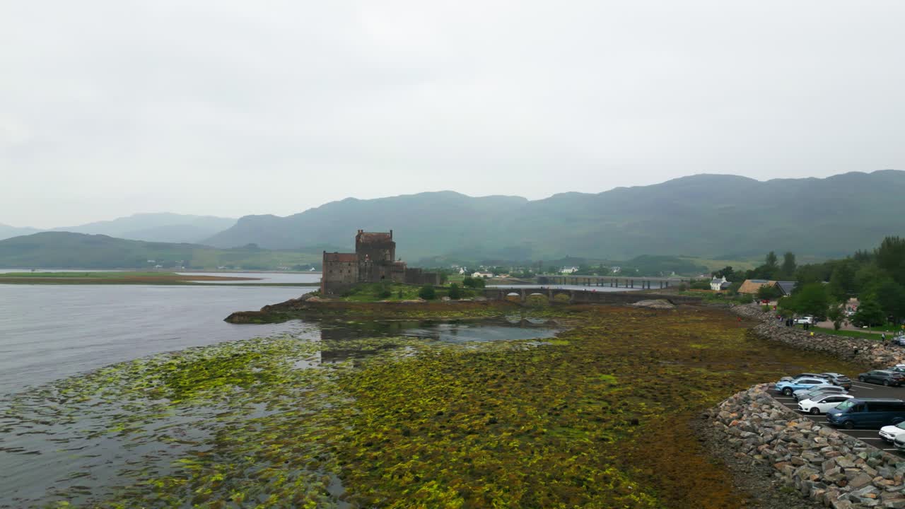 Drone flies around Eilean Donan Castle in the Scottish Highlands on a cloudy summer day