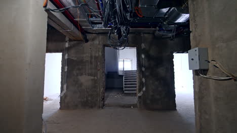 Walking by the corridor of the building under reconstruction. Tour by the rooms with bare walls approaching the stairs.