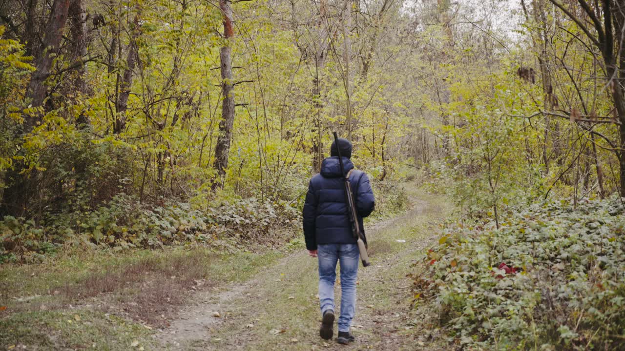 Man shooting gun in forest. Close up of male hunter in the forest aiming and shooting with hunting rifle