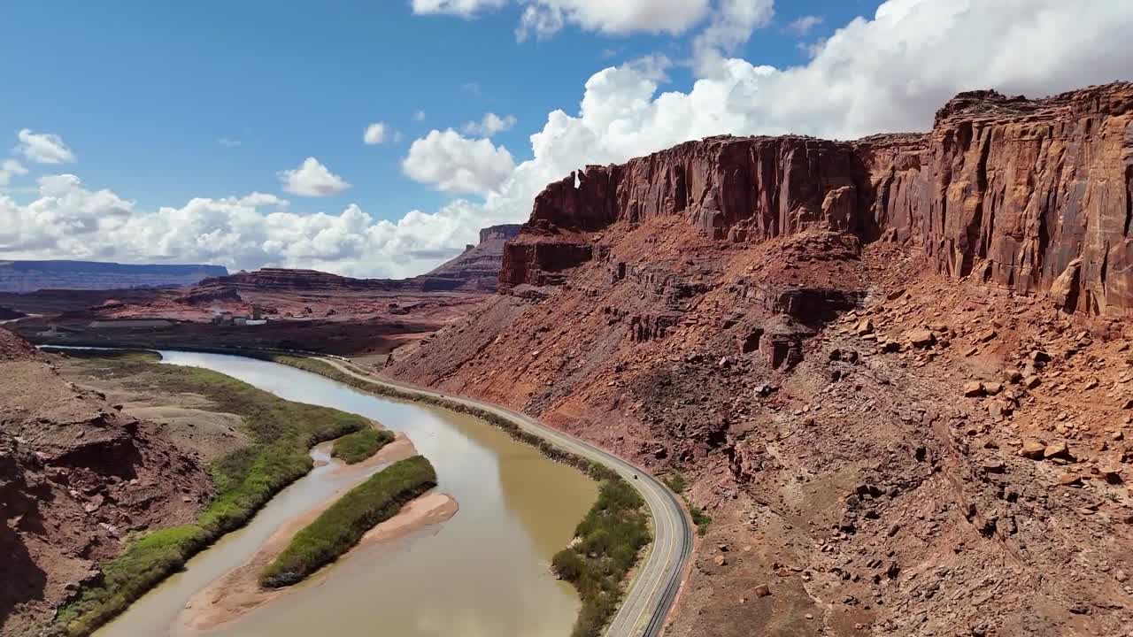 Aerial View of Highway in Desert next to Railroad Tracks, Tall Red Buttes in Background, Colorado River, Potash Road in Moab Utah