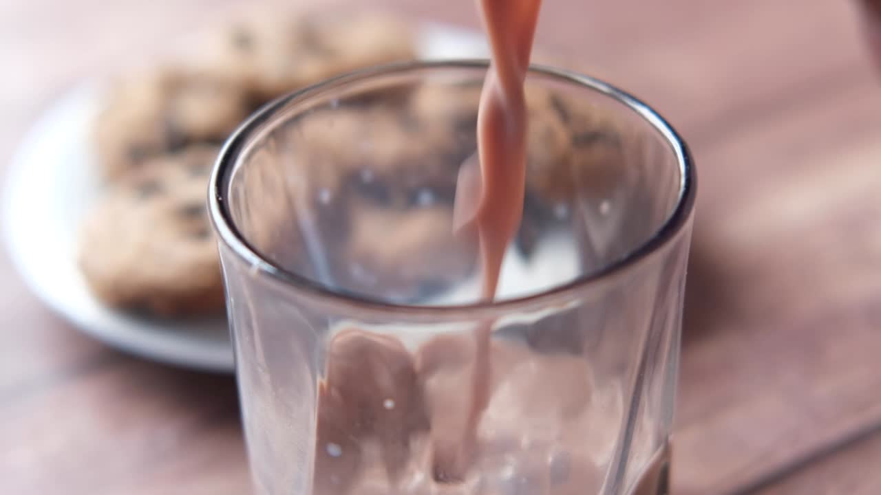 Latte al cioccolato versato in un bicchiere con biscotti