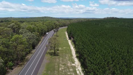 Drone-Ascendiendo-Sobre-Una-Carretera-Y-Un-Bosque