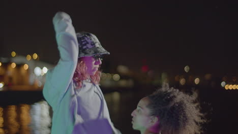 dos jóvenes bailando en el paseo marítimo por la noche