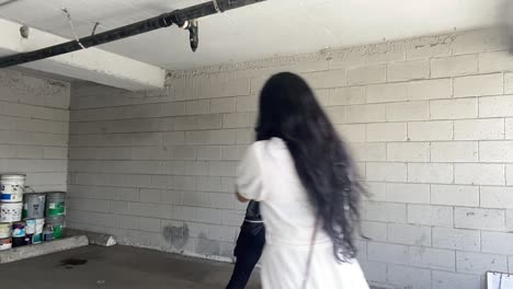 videographers film a woman in a yellow dress dripping candle-wax in her mouth against a white brick backdrop